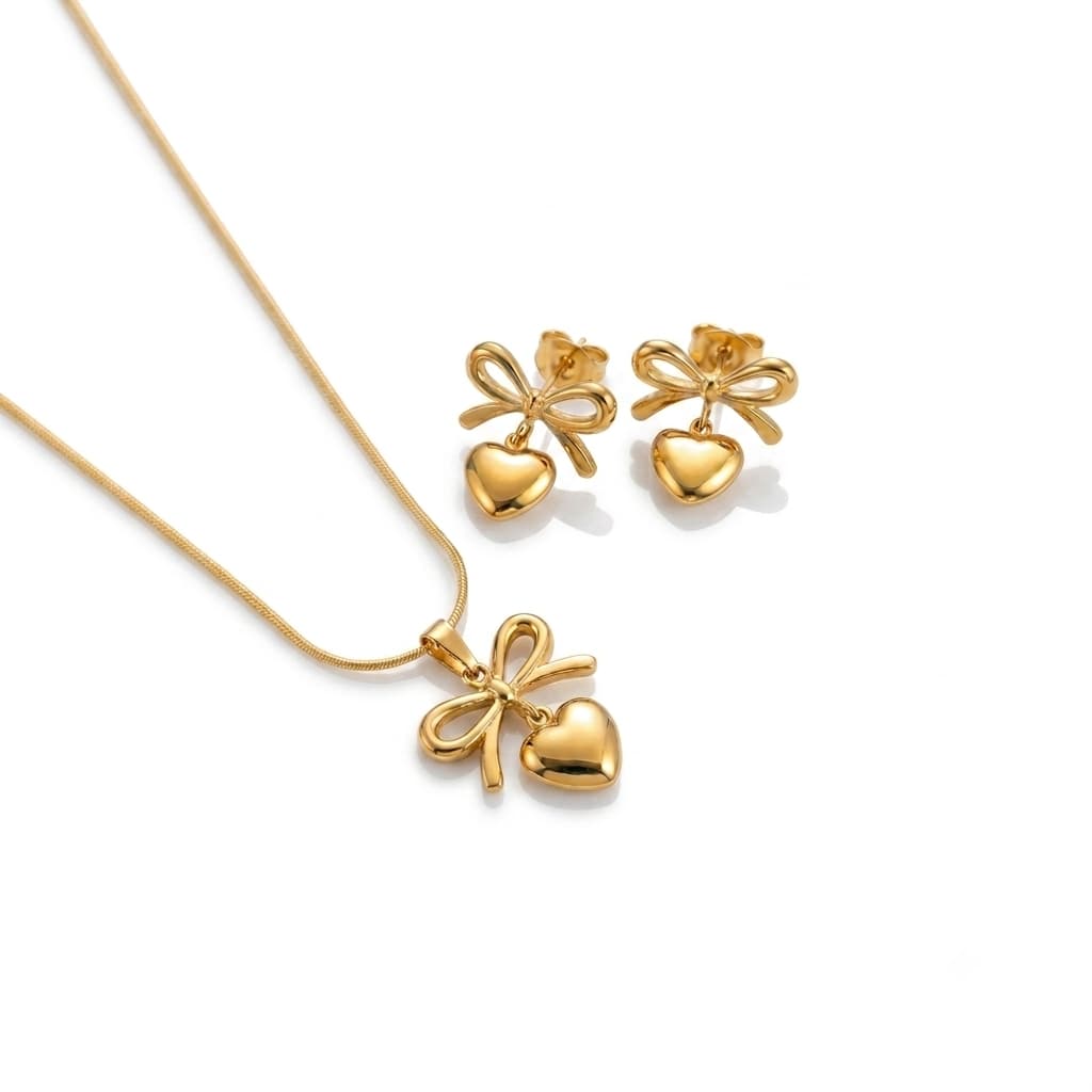 Gold necklace and earrings with heart and bow designs on a white background