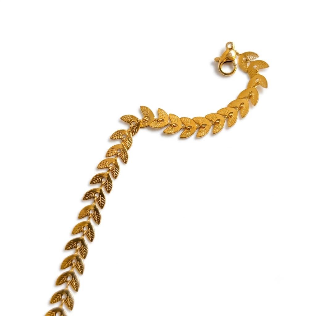 Gold bracelet with leaf pattern on a white background